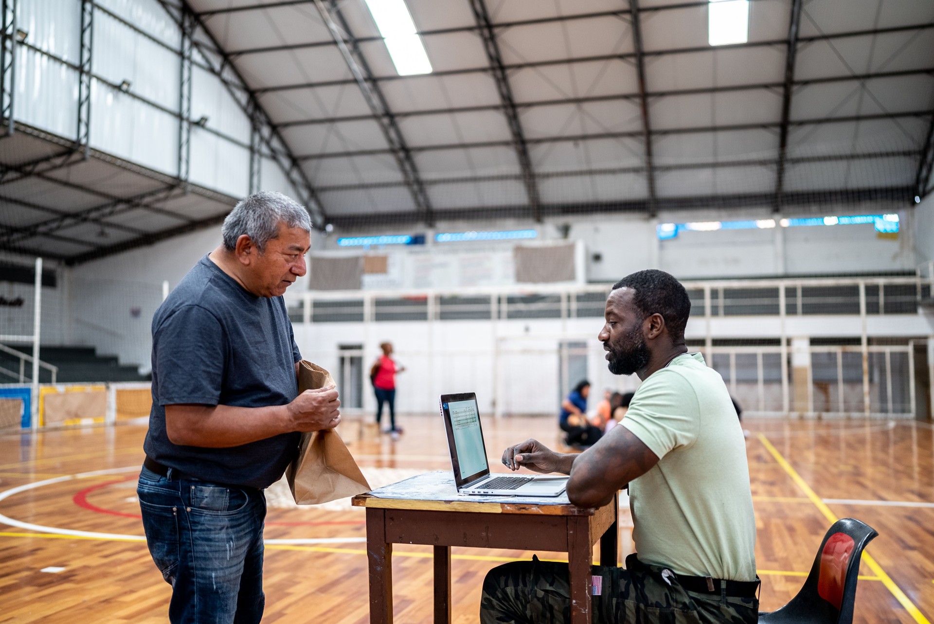 Soldier talking with a refugee disability man while using the laptop at a refugee sheltering
