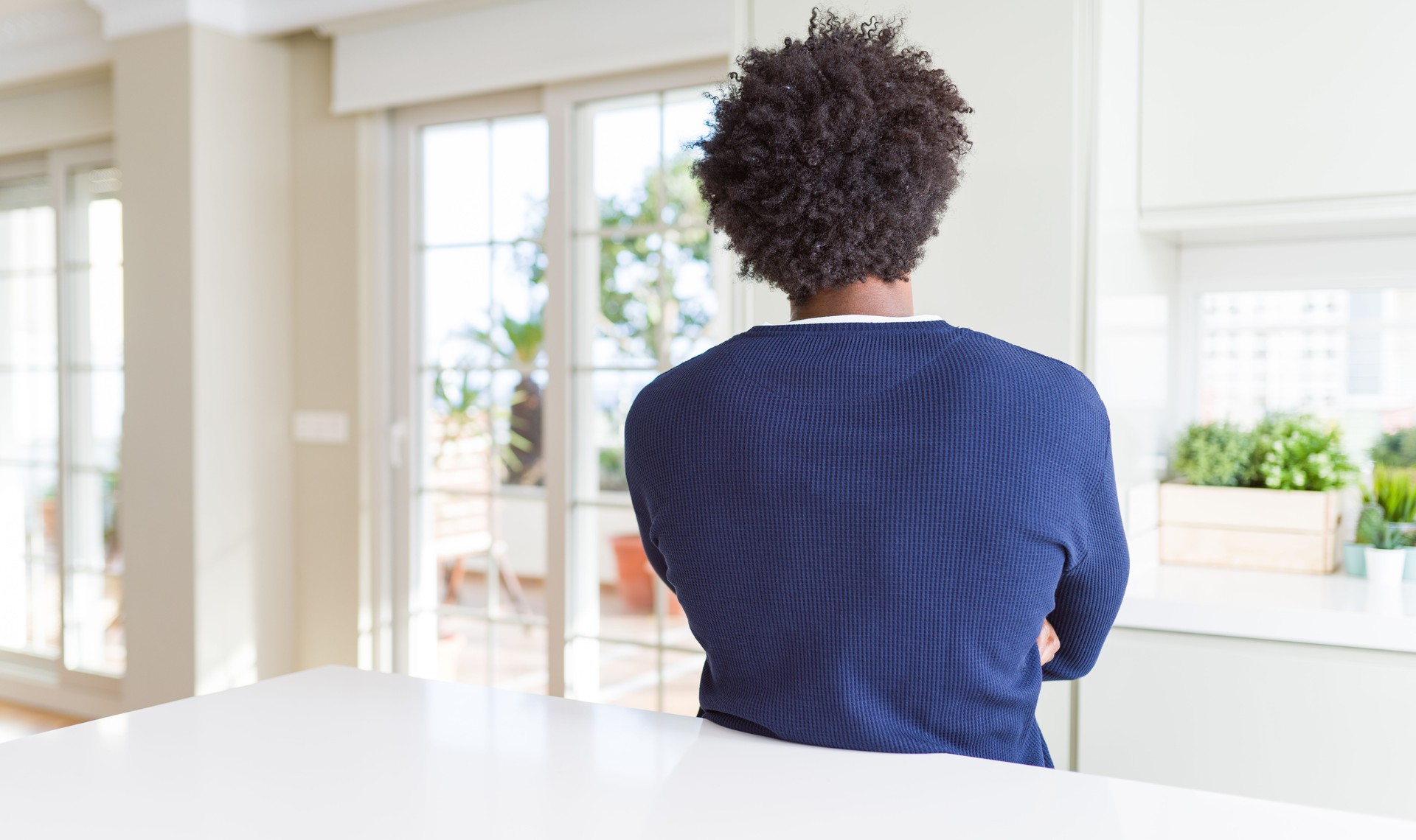 Young african american man wearing casual sweater sitting at home standing backwards looking away with crossed arms